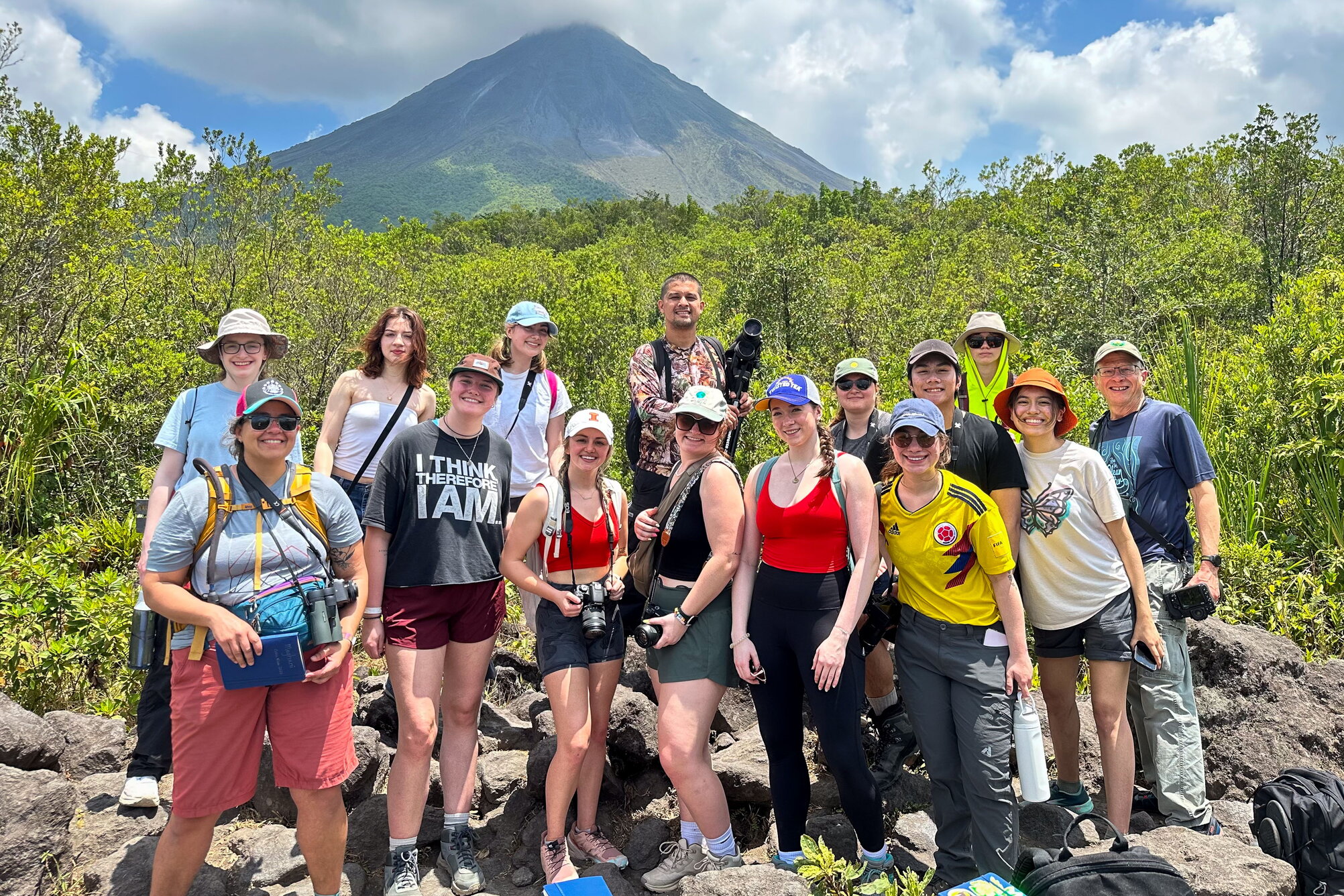 A group posing for a picture in front of a volcano very far in the distance.