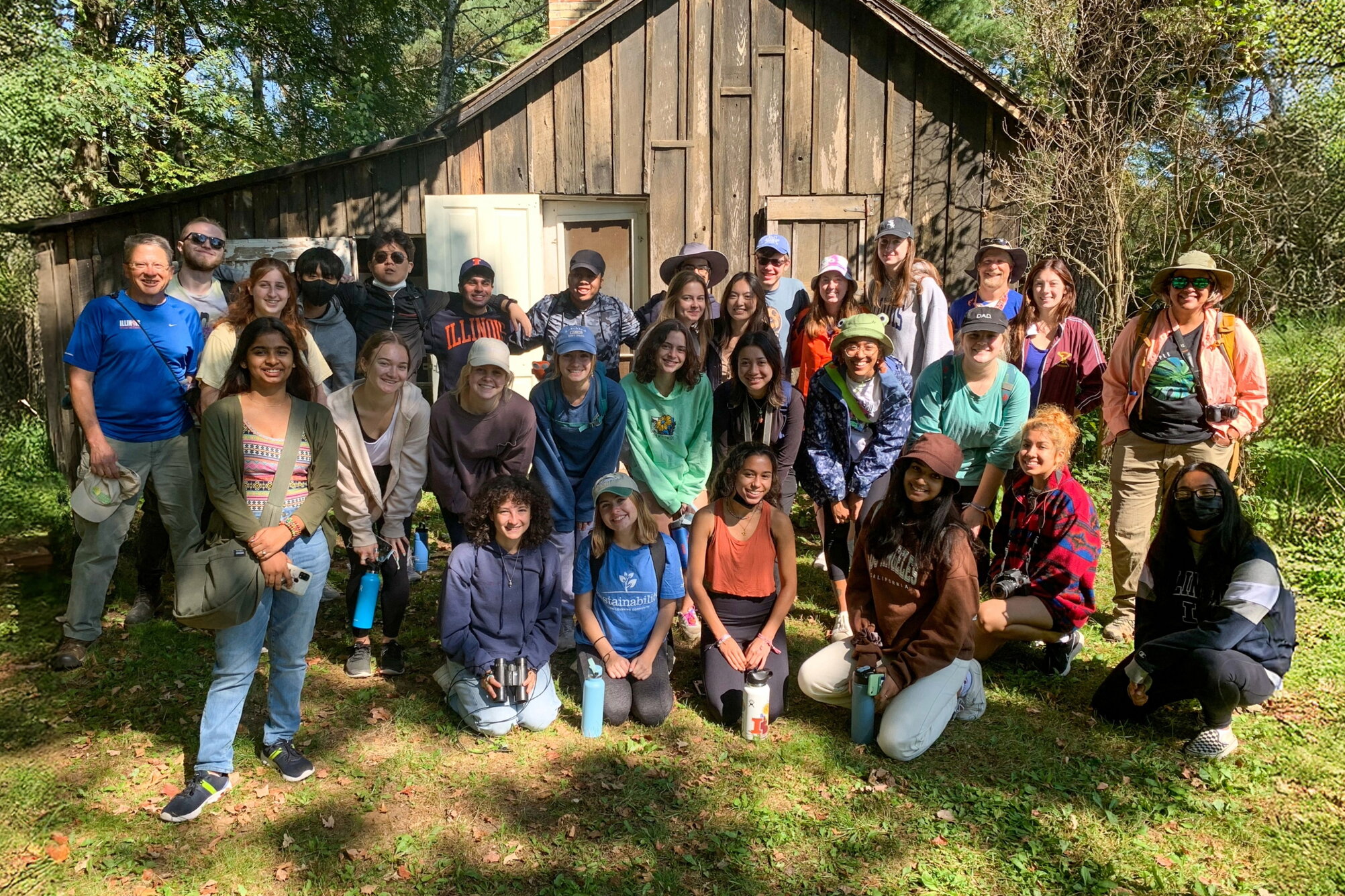 A group of students posing in front of a cabin.